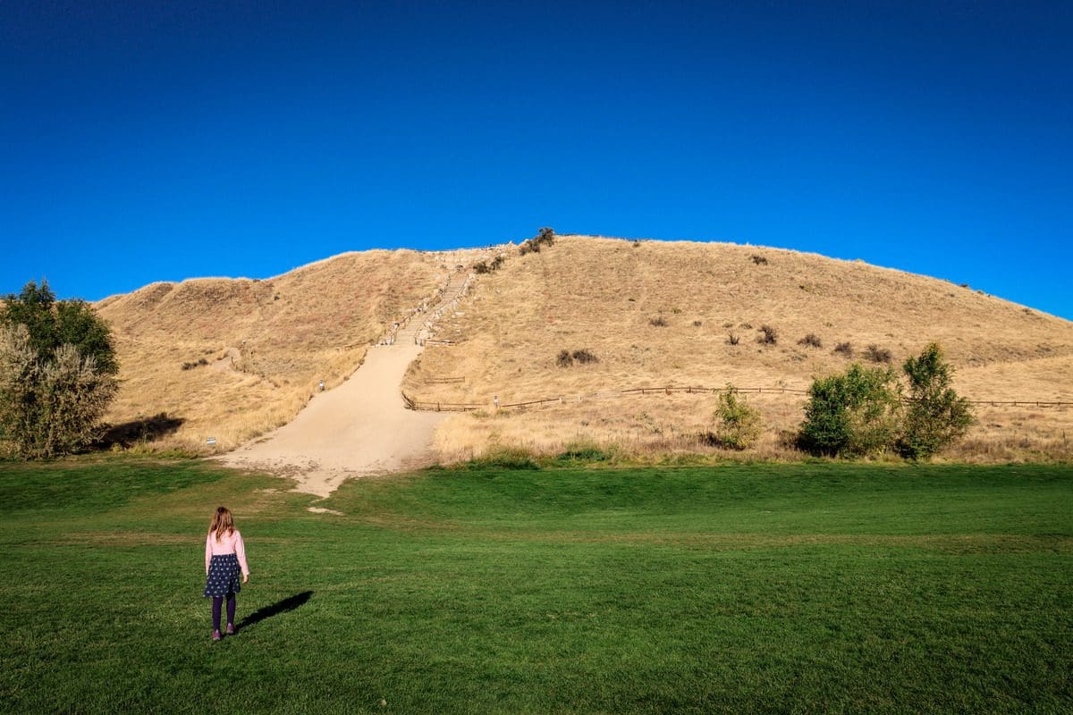 A young girl walks toward the trailhead for one of the hiking paths at Camel's Back Park, one of the best things to do in Boise with kids.