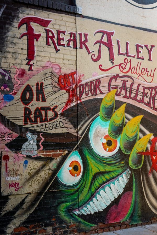 A mural of a monster peeling back the bricks at the entrance of the Freak Alley Gallery.
