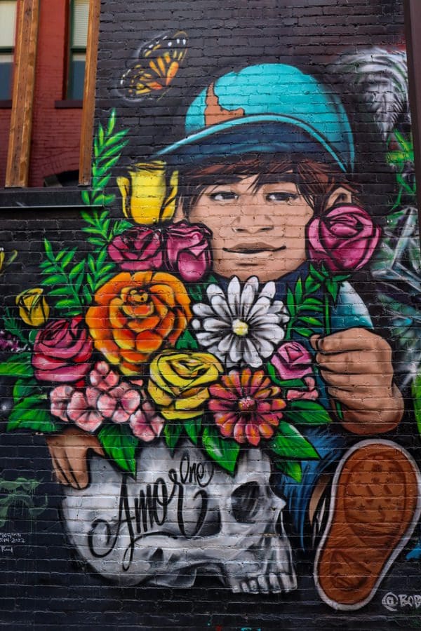 One of the colorful murals part of the Freak Alley Gallery, featuring someone holding a large assortment of flowers coming from a human skull.