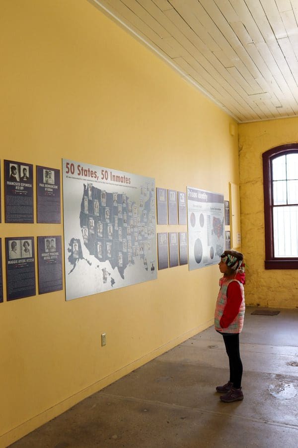 A young girl reads exhibit information about past inmates of the Old Idaho Penitentiary, one of the best things to do in Boise with kids.