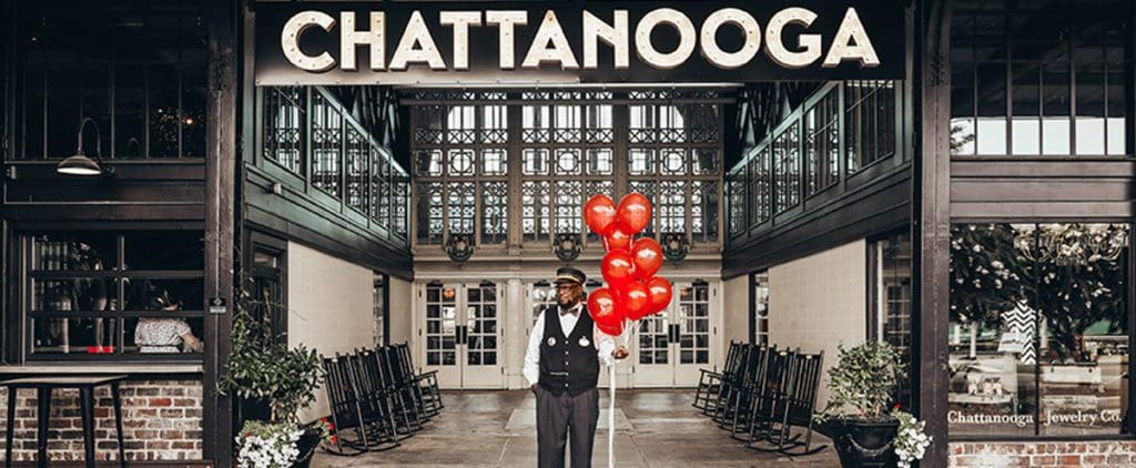 A man holding red balloons stands outside of Chattanooga Choo Choo.