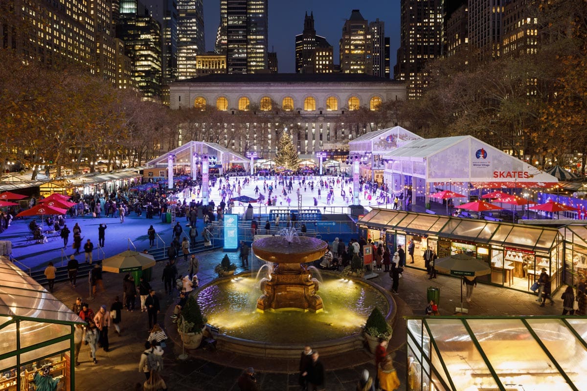 Several people skate in the outdoor rink at a Bank of America Winter Village at Bryant Park, one of the best Christmas Markets in the United States for families.