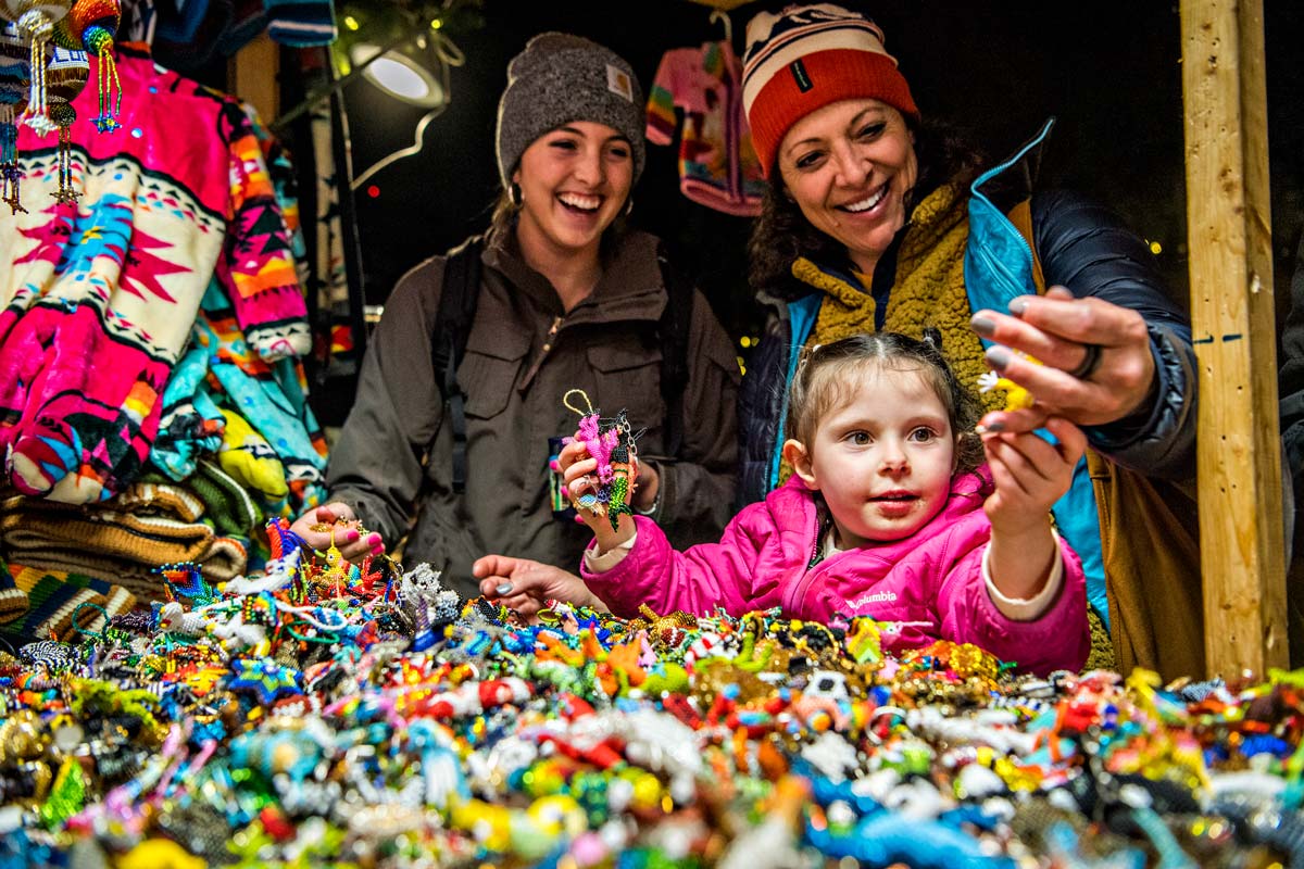A family look at kids' jewelry at a vendor at Denver Christkindlmarket.
