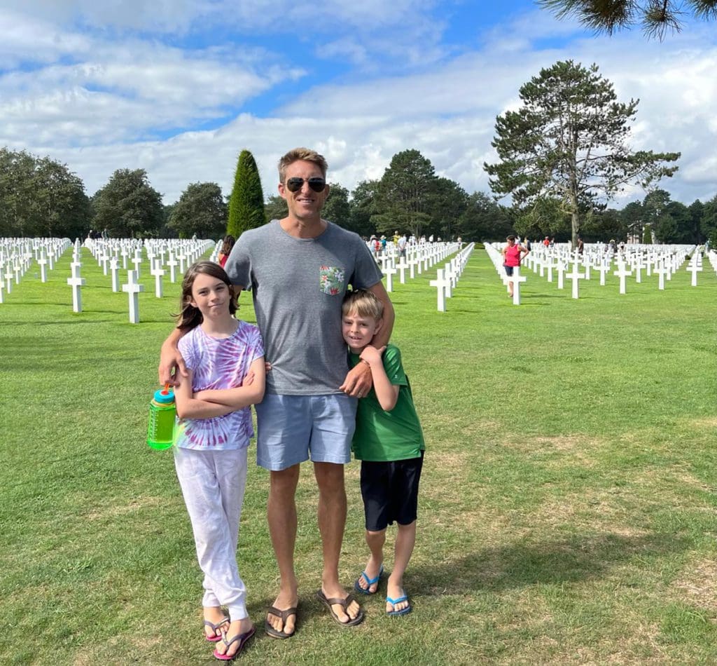 A dad and his two kids stand together at the Omaha Beach Cemetery, one of the best museums in France with kids.