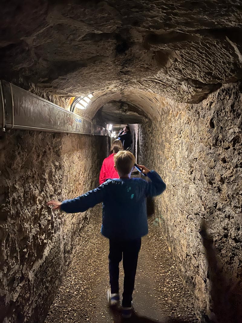 A young boy walks through the Catacombs of France on a tour.