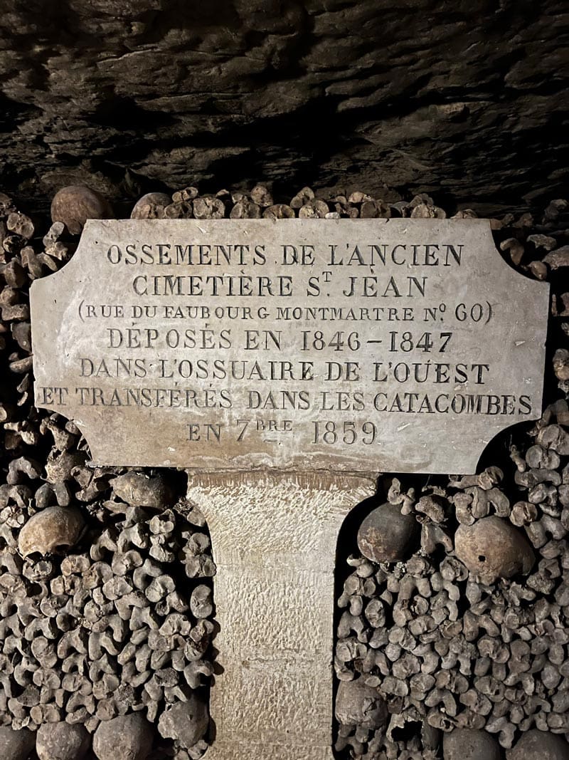 A sign within the catacombs of France, written in French, and surrounded by bones.