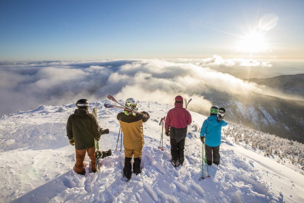 Four skiers look out over a snowy mountain while skiing at Sugarloaf Mountain Resort.