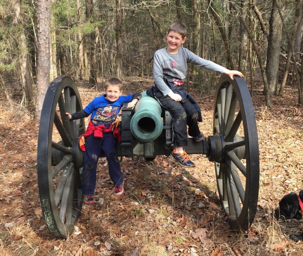 Two kids sit on a cannon, part of a display at Chickamauga Battlefield.