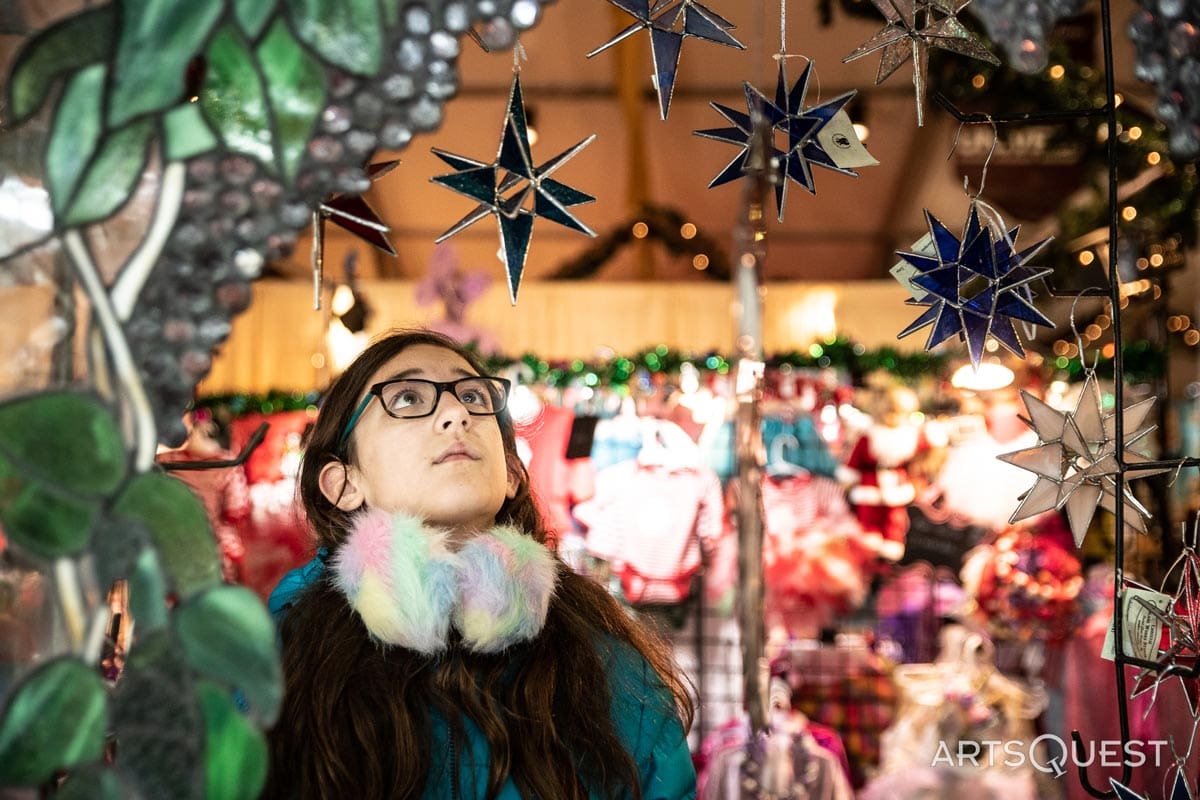 A young girl looks up at holiday decor at a vendor stall at Christkindlmarkt Bethlehem.
