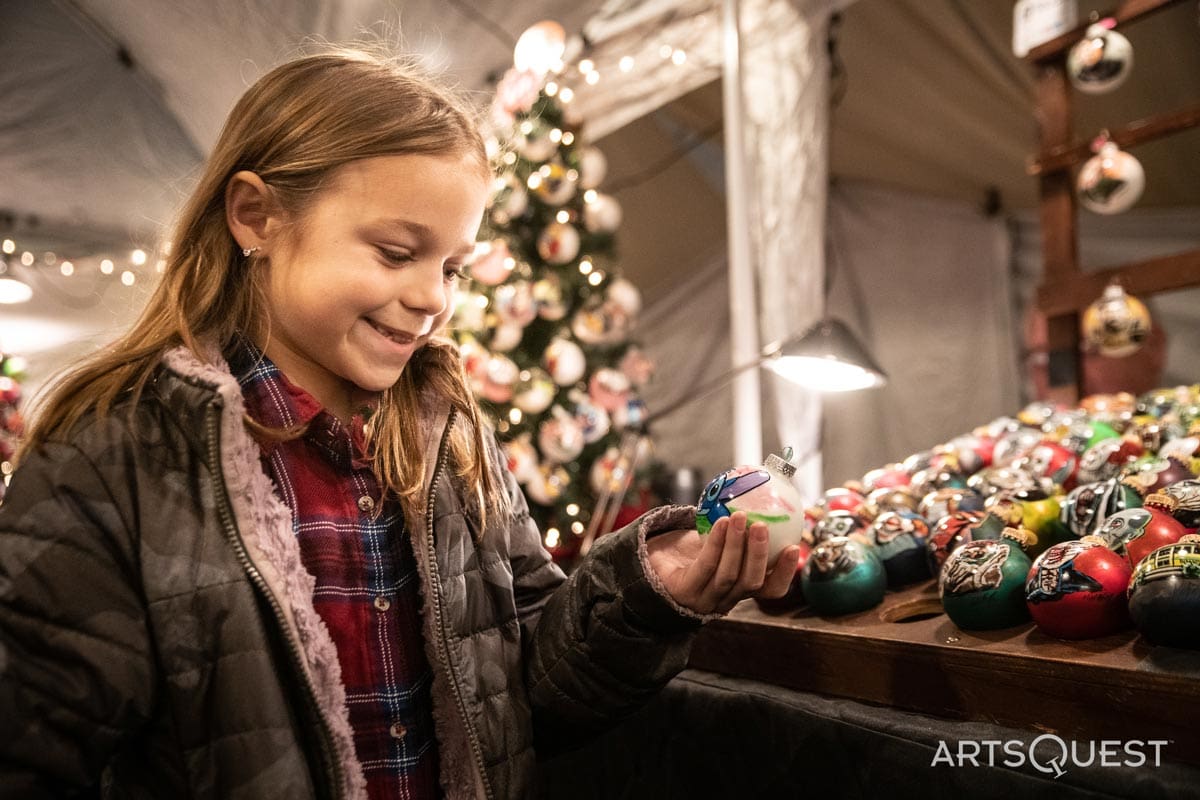 A young girl holds a Christmas ornament at the Christkindlmarkt Bethlehem, one of the best christmas markets in the United States for families.