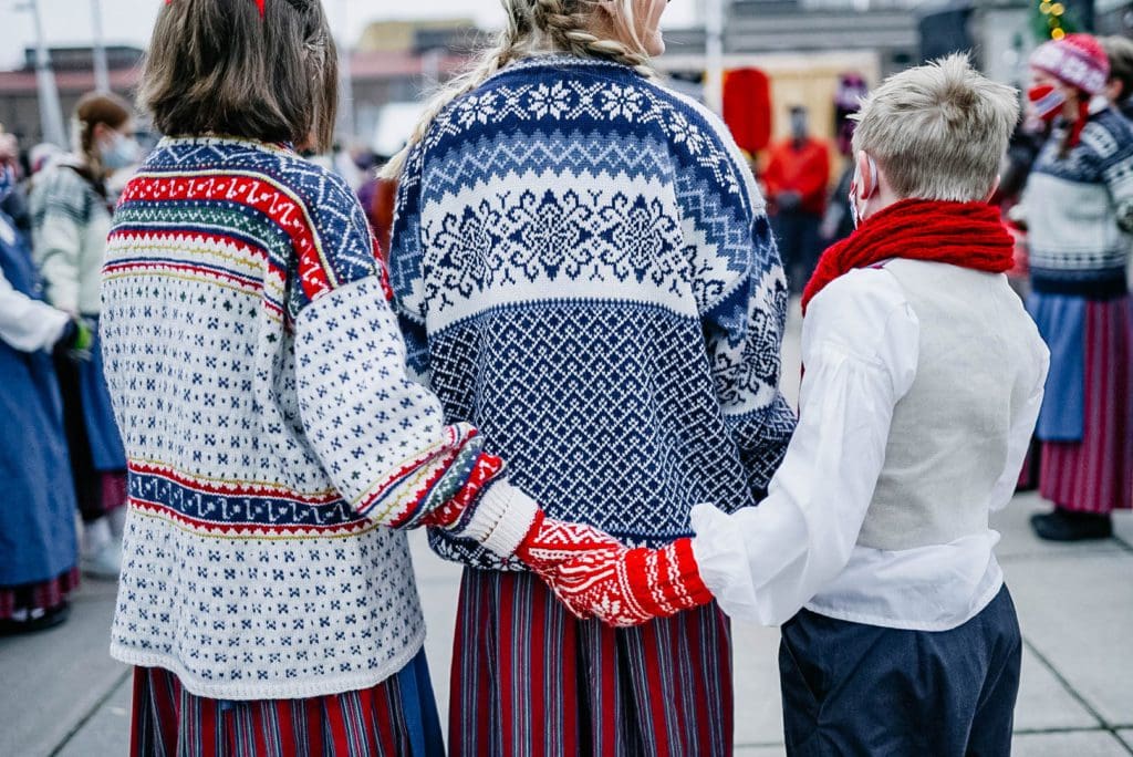 Three kids dressed in Scandinavian sweaters stand together at the St. Paul European Christmas Market, one of the best christmas markets in the United States for families.