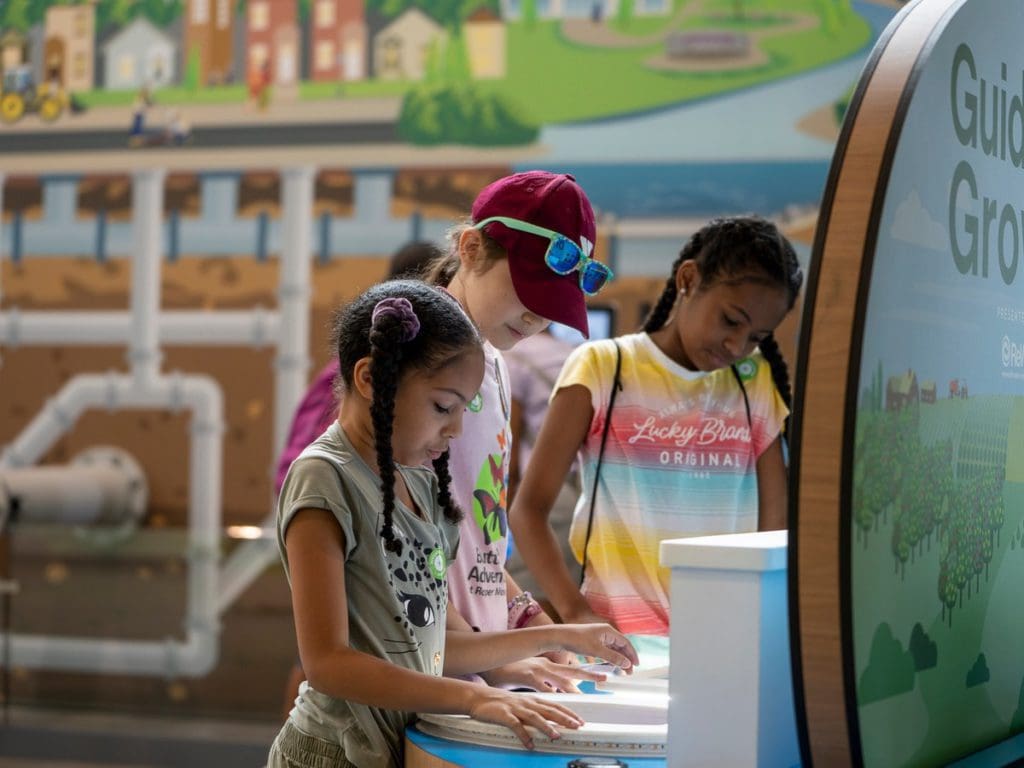 Three kids work at an exhibit in the Roper Mountain Science Center.