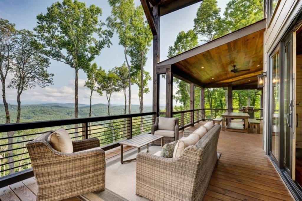 The deck off a cabin at Southern Comfort Cabin Rentals, featuring a cozy seating area and views of the North Georgia Mountains.