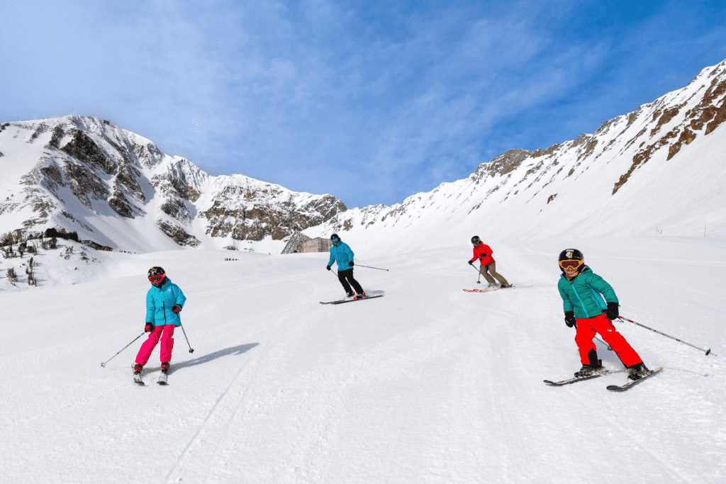 A family of four zooms down an alpine slope while skiing in Big Sky with kids.