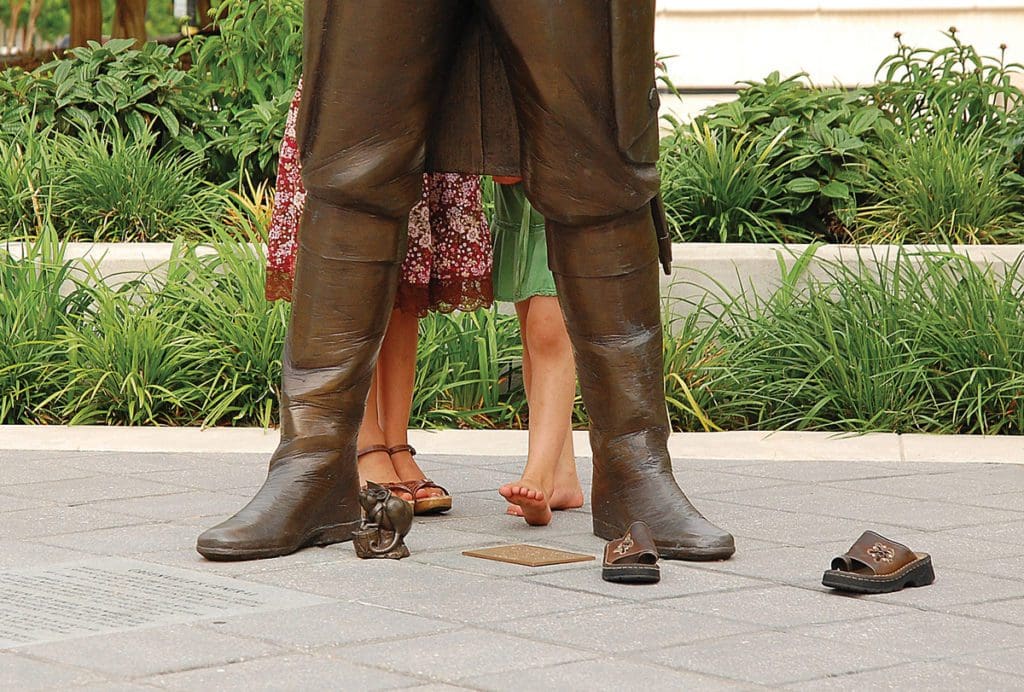 Kids feet shown behind the feet of a statue found while exploring Heritage Green, one of the best things to do in Greenville, South Carolina with kids.