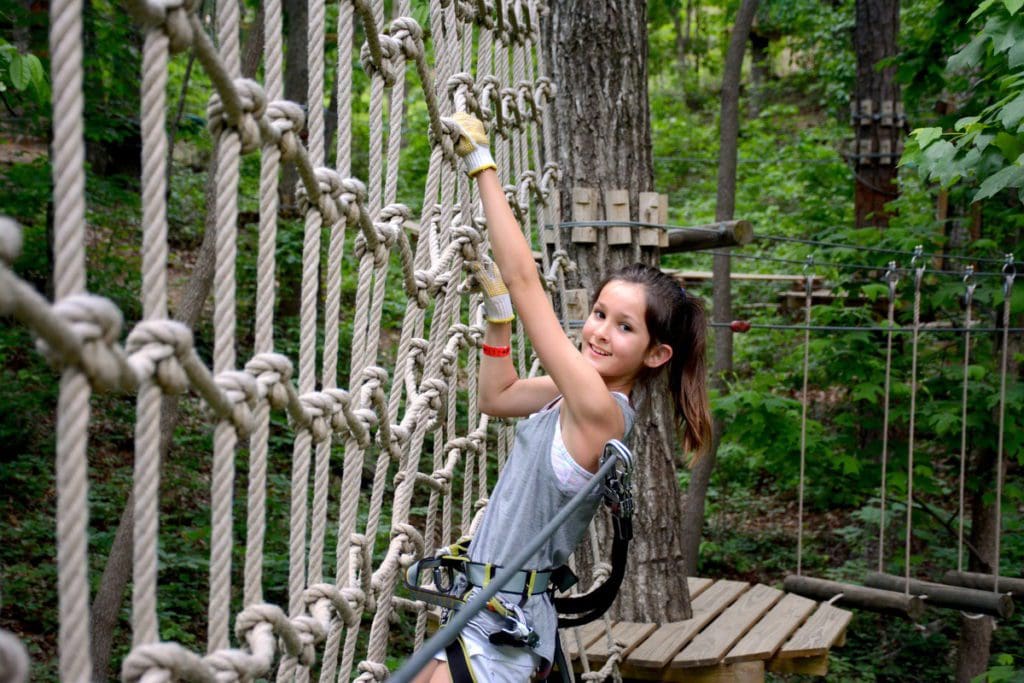 A young girl makes her way across a course at the TreeTop Quest.