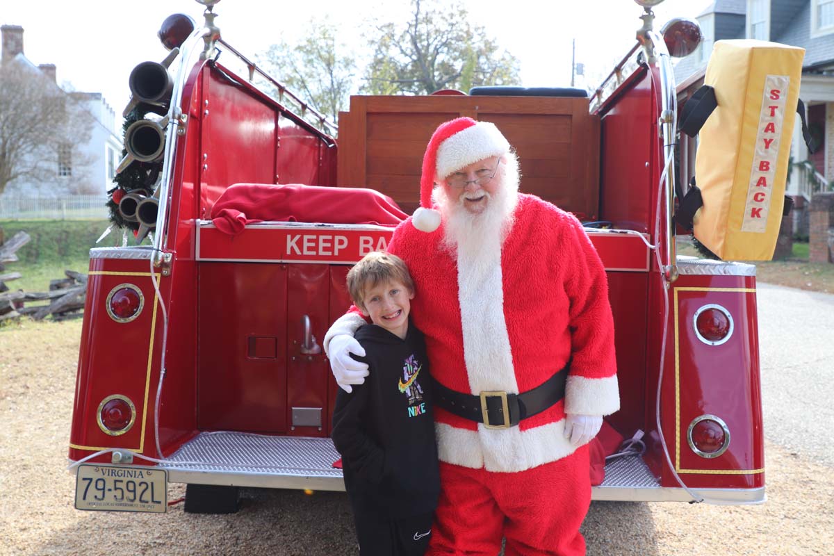 A young boy poses with Santa at Christmas Market on Main, one of the best christmas markets in the United States for families.