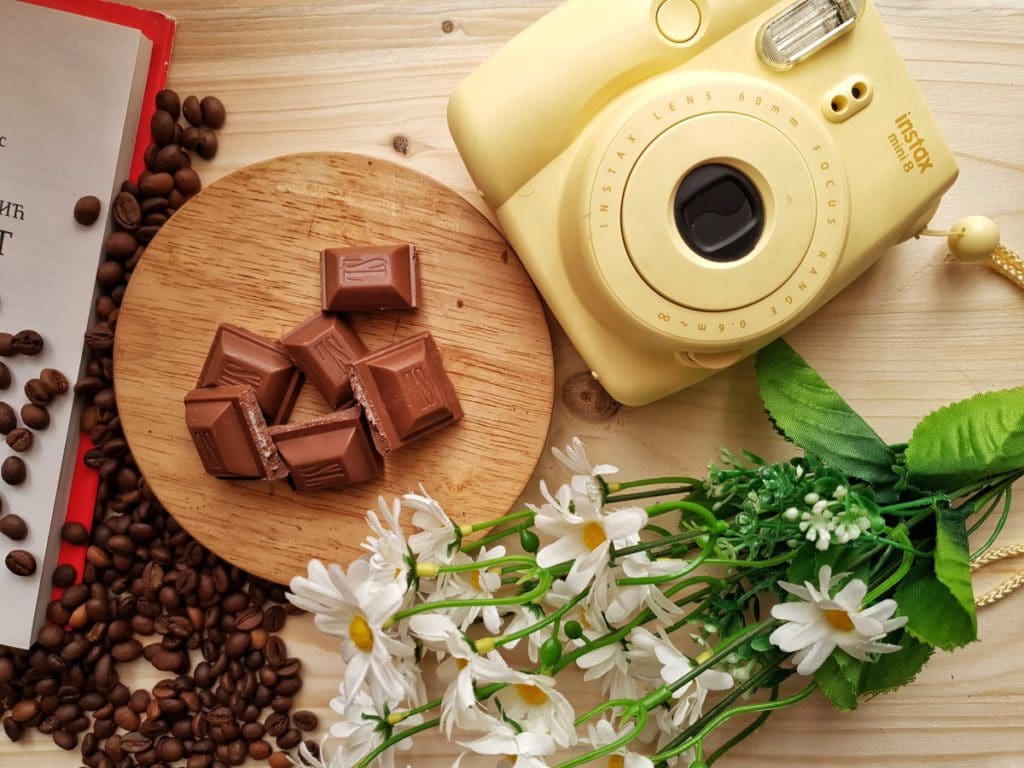A table is set with chocolates and fresh flowers, with a camera laid on the table as well.