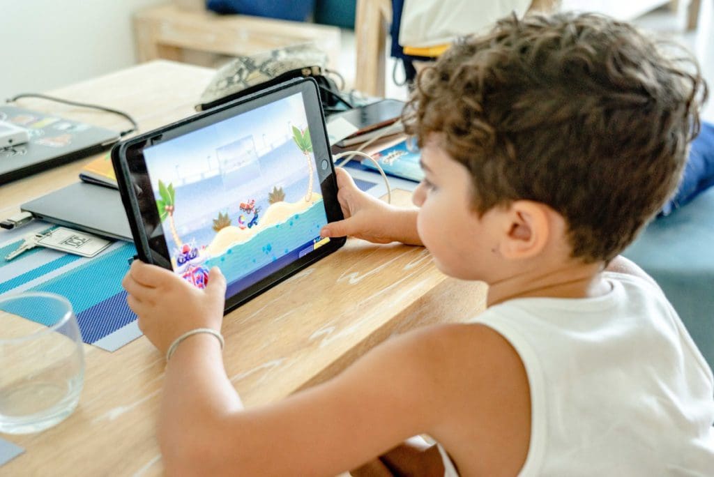 A young boy plays a game on an iPad, one of the best family travel gifts.