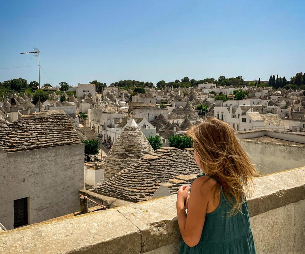 A young girl looks out over the rooftops of the famous trulli of Alberobello, one of the best places to visit in Puglia with kids.
