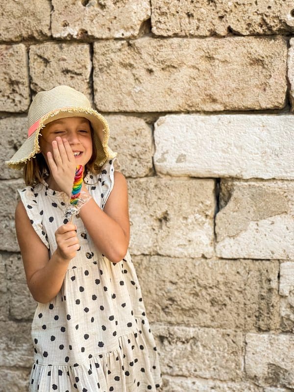 A young girl smiles as she enjoys a large sucker in Bari.