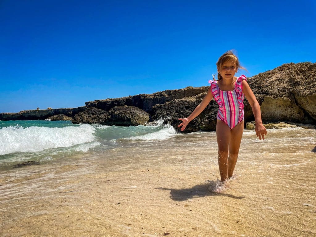 A young girl runs along a beach in Monopoli, one of the best places to visit in Puglia with kids.
