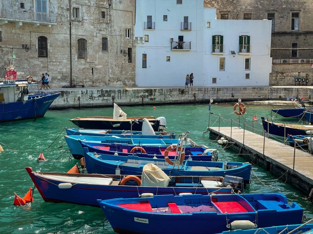 Colorful traditional fishing boats float in the port of Monopoli, one of the best places to visit in Puglia with kids.