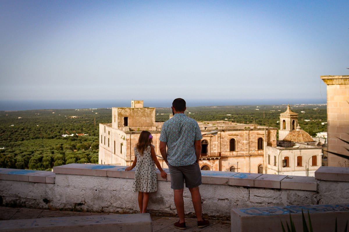 A dad and his young daughter look out over a view below Ostuni from the Old Town walls.