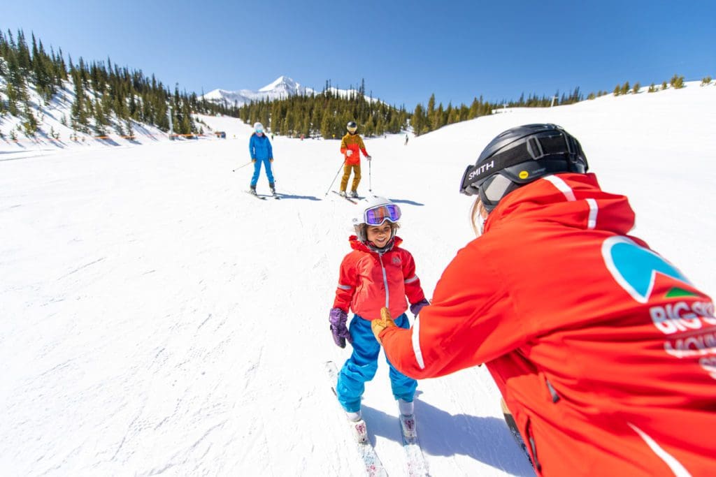 A ski instructor leads a child down a slope at Big Sky Resort.