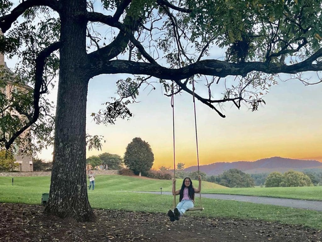 A young girl swings on a tree swing at the Biltmore Estate, one of the best things to do in Asheville with kids.
