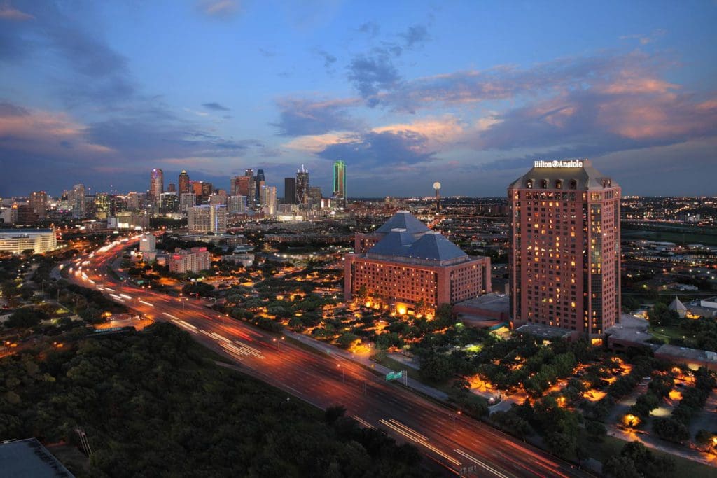 Aerial view of the Dallas skyline at night, including the Hilton Anatole, one of the best hotels in Dallas for families.