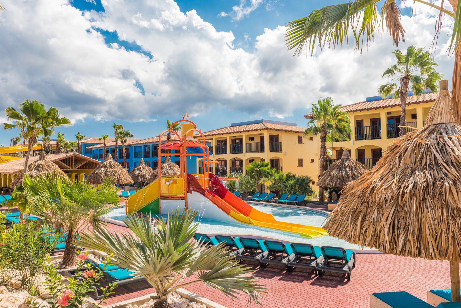 The colorful on-site playground, surrounded by resort buildings, at Kunuku Aqua Resort Curacao - Trademark by Wyndham.