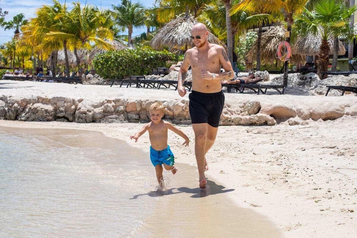 A toddler and his dad run along the beach at LionsDive Beach Resort.