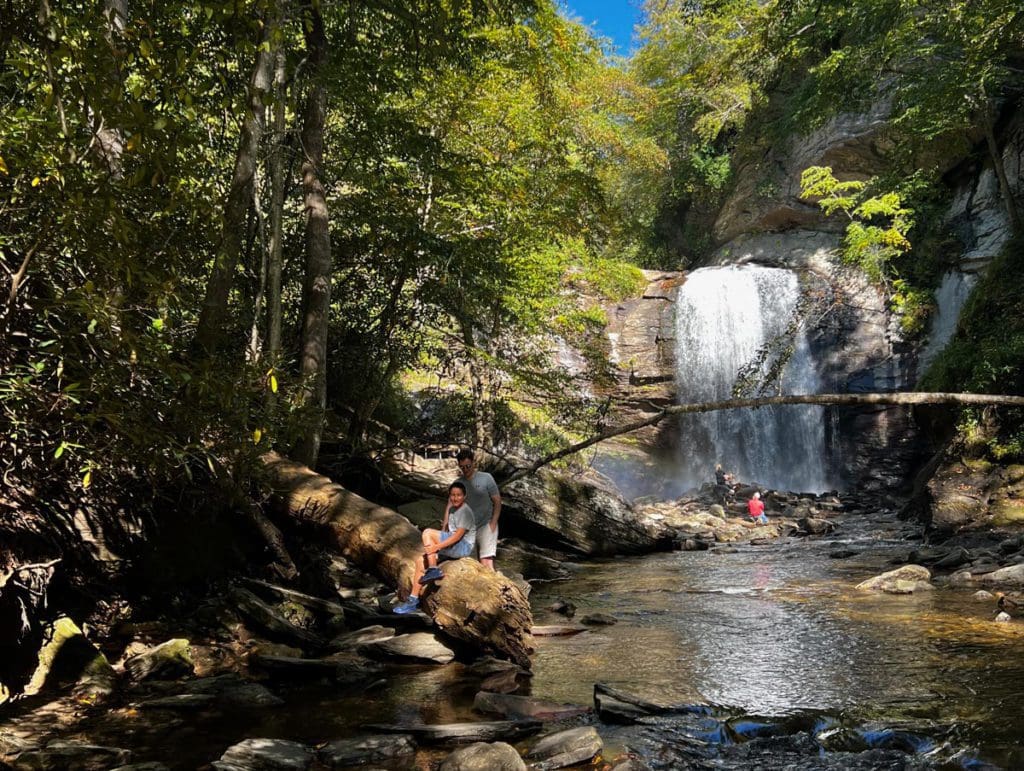 People explore the base of a waterfall near Looking Glass Falls in Asheville, a must stop on any Asheville family vacation itinerary.