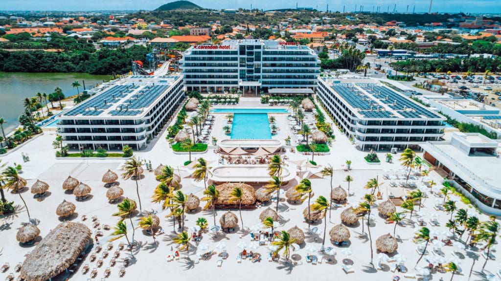 An aerial view of Mangrove Beach Corendon Curacao All-Inclusive Resort, Curio Collection, featuring a large resort building, outdoor pool, beach access, and more, at one of the best Curacao resorts with kids.