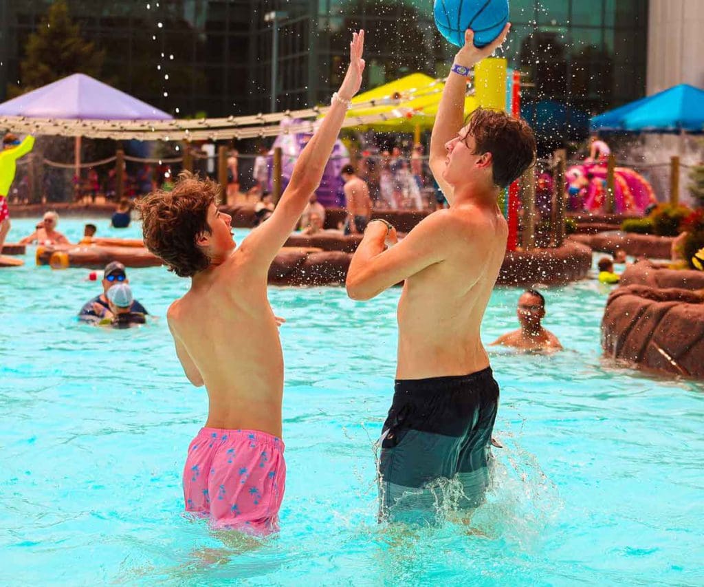 Two teenagers play water basketball in a pool at Massanutten Resort, one of the best water parks near Washington DC for families.