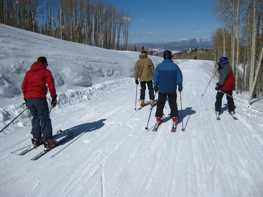 Four people ski along an alpine trail at Park City Mountain Resort.