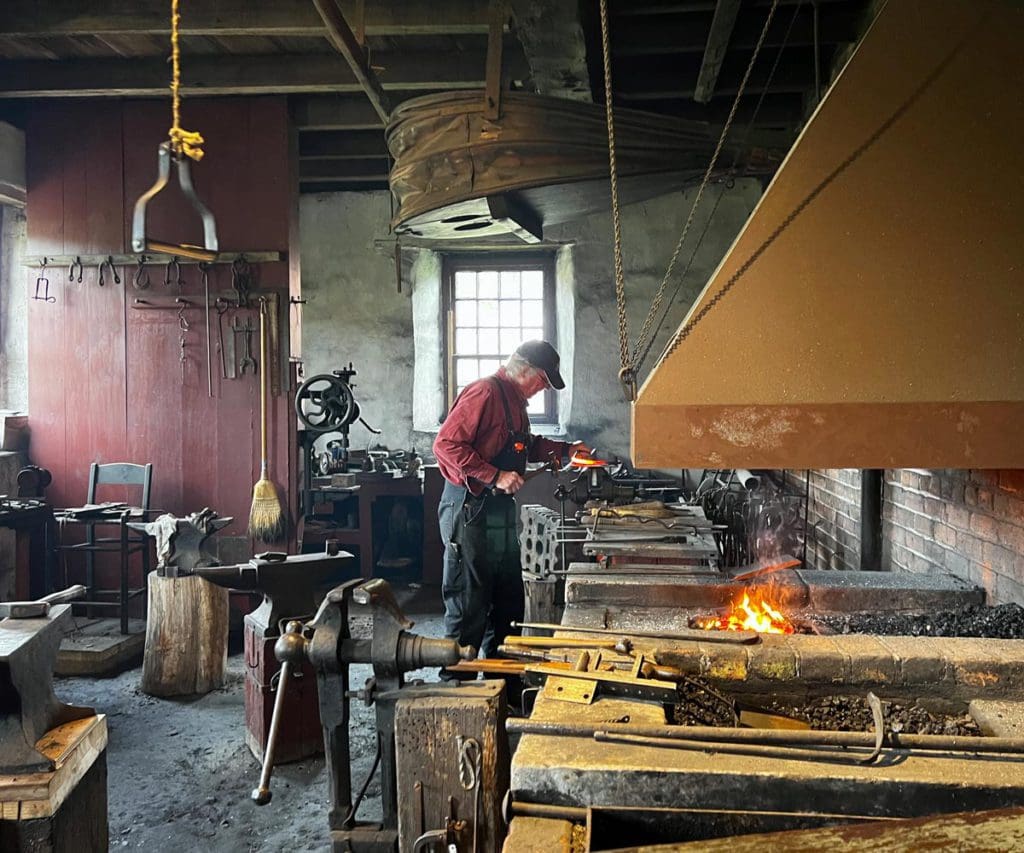 A man works at a blacksmith's table and gives a demonstration.