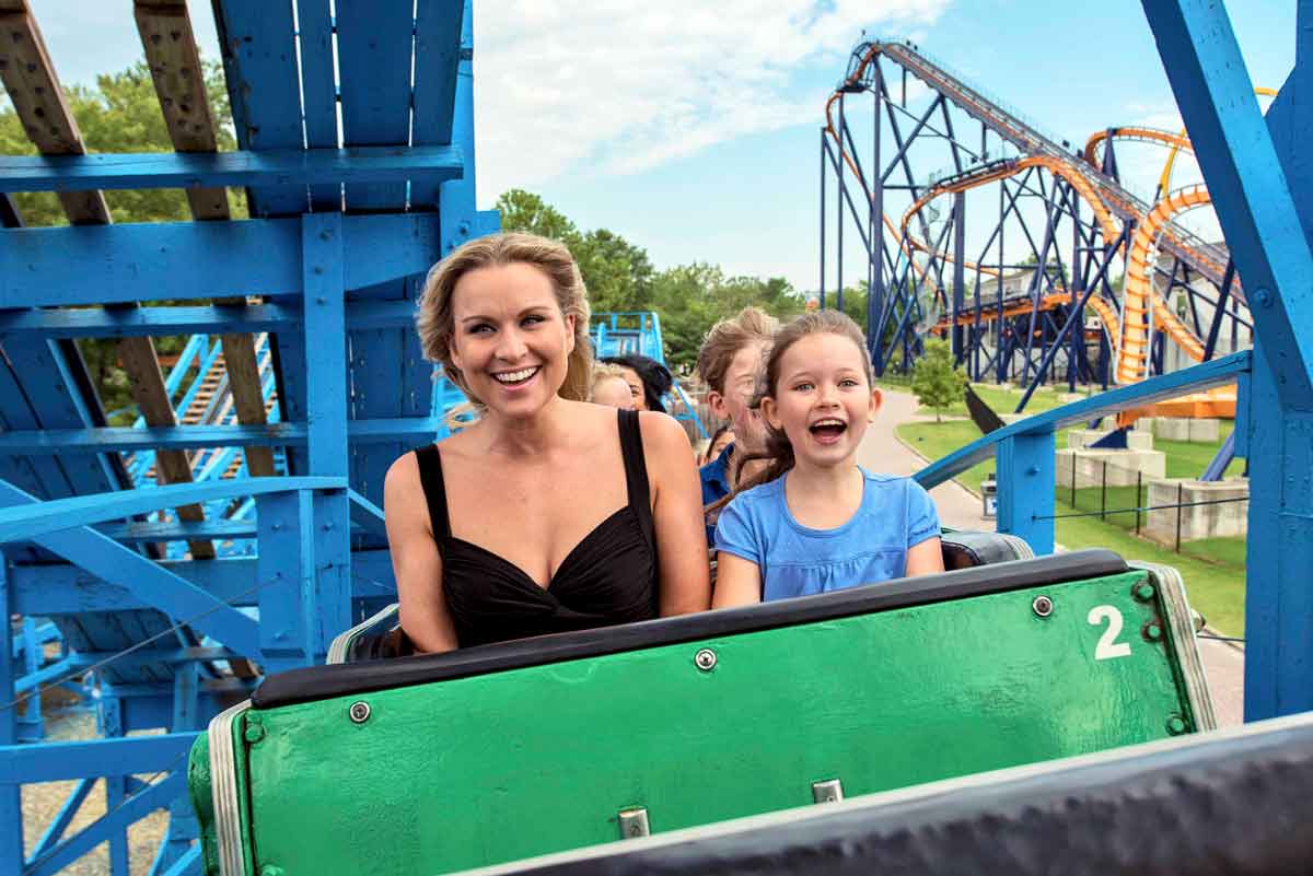 A mom and daughter smile brightly as they enjoy a roller coaster ride at Kings Dominion, one of the best water parks near Washington DC for families.