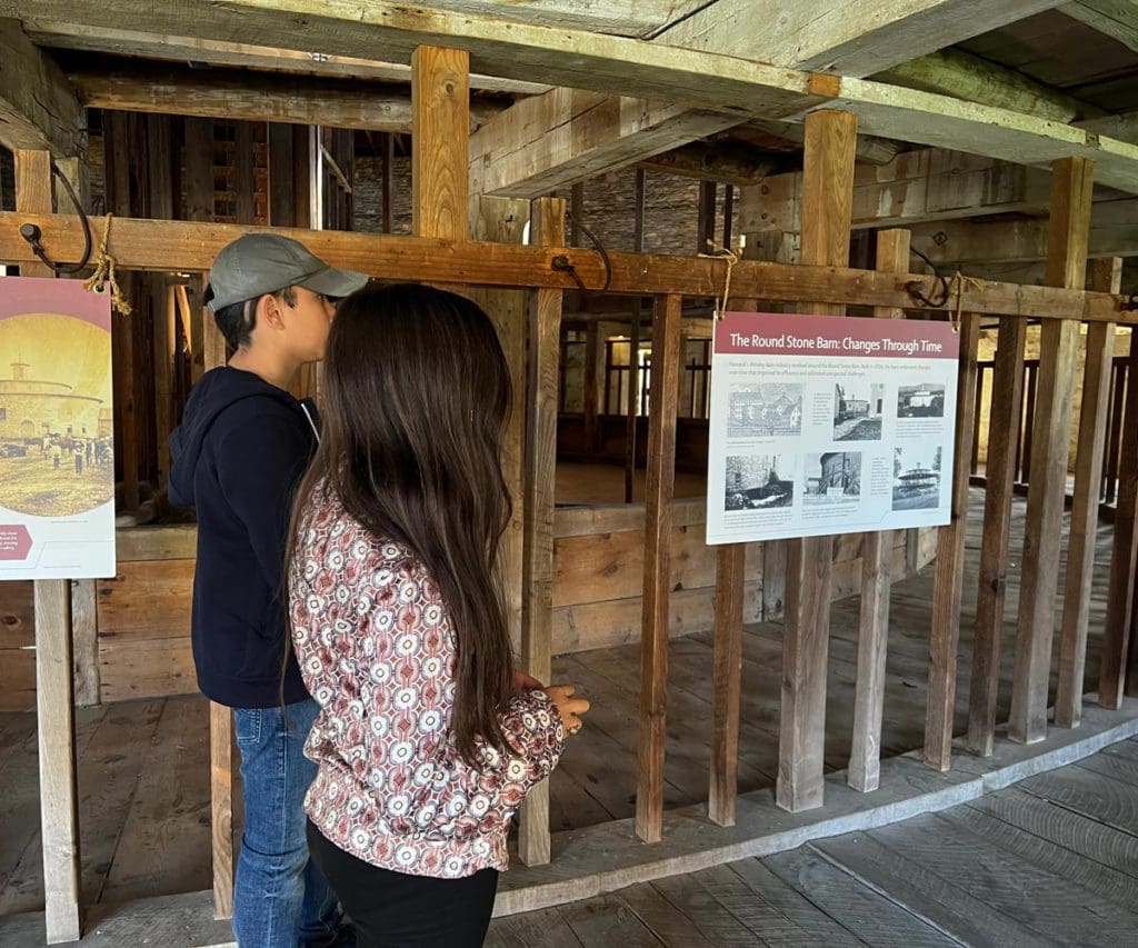 Two kids read an exhibit plaque inside the Round Stone Barn.