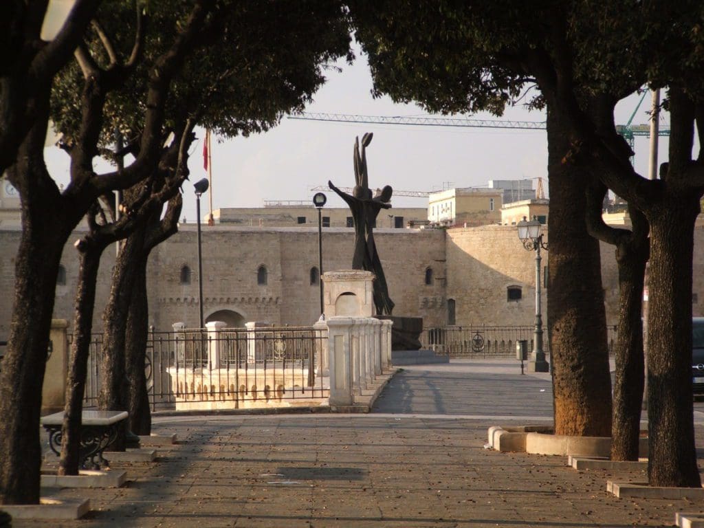 A statue along a tree-lined path in Taranto.