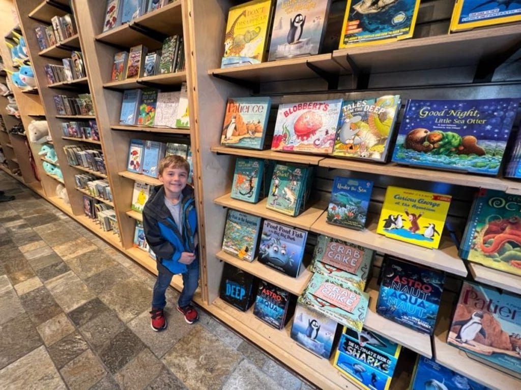 A young boy stands near a shelf filled with books in the gift store at Monterey Bay Aquarium.