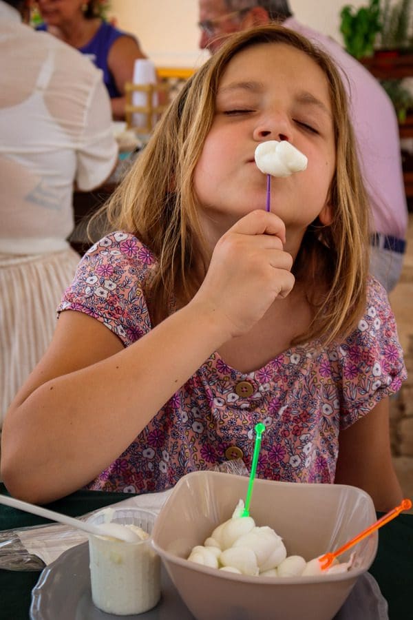 A young girl samples fresh mozzarella at a masseria in Puglia, knowing what to eat is one of the essential tips for visiting Puglia with kids.