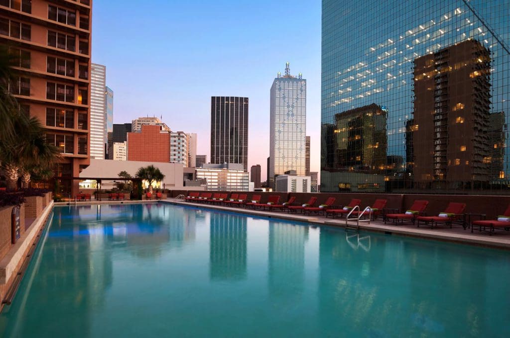 The sleek rooftop pool overlooking the Dallas skyline at dusk at Fairmont Dallas, one of the best hotels in Dallas for families.