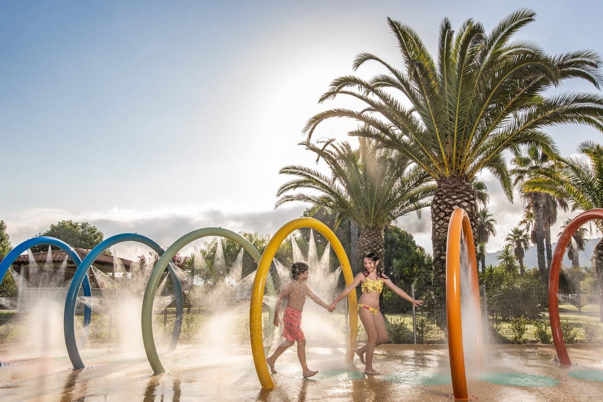 Kids running through a splash water feature at Falkensteiner Club Funimation Garden Calabria.