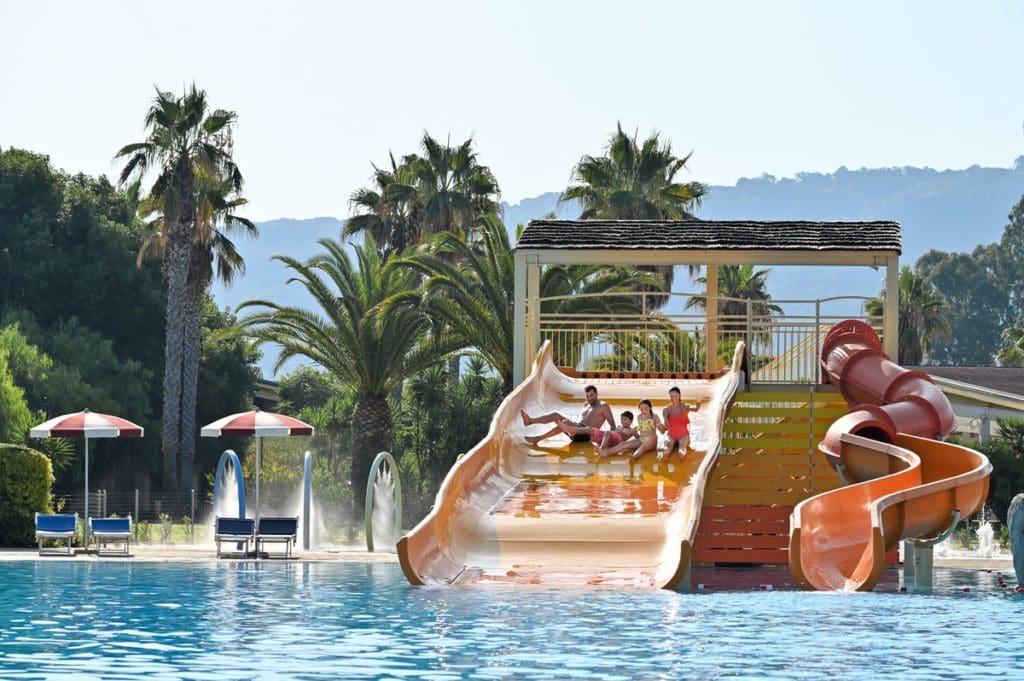 Kids soar down a waterslide at the outdoor pool at Falkensteiner Club Funimation Garden Calabria, one of the best all-Inclusive family vacation spots in Europe.