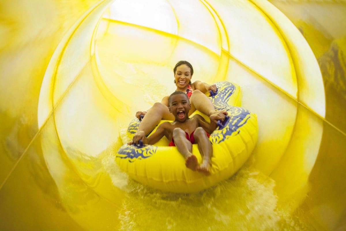 A mom and her young son race down an indoor waterslide together at Great Wolf Lodge Grapevine.