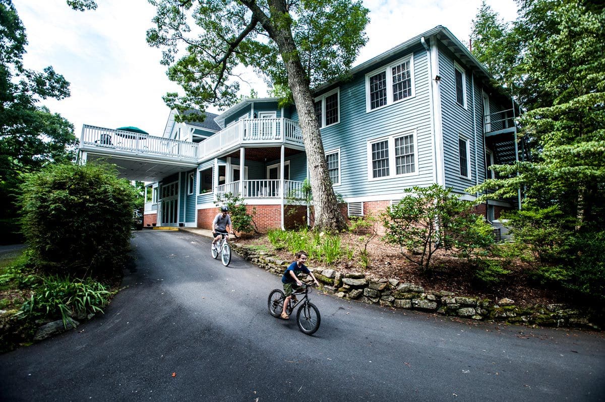 Two people biking away from the entrance at Highland Lake Inn & Resort – Flat Rock.