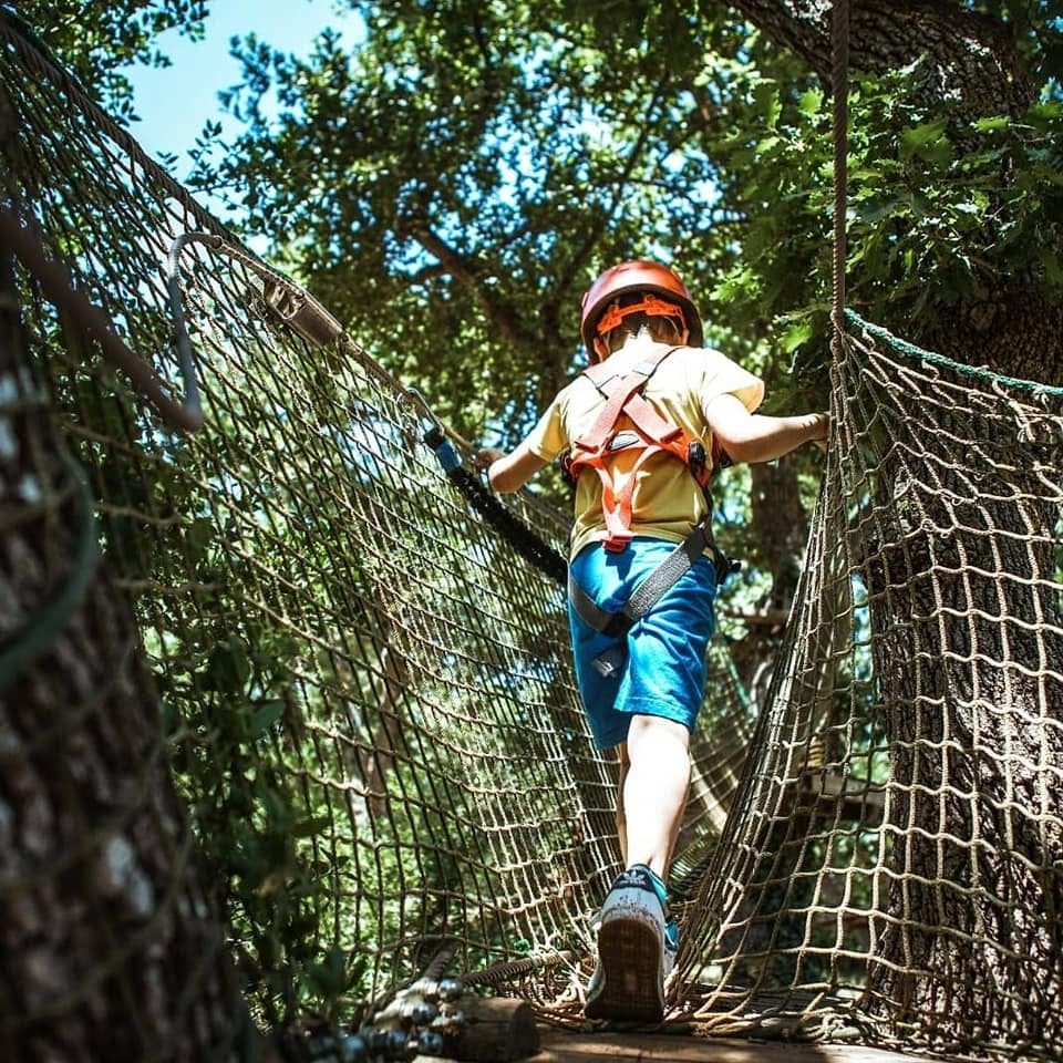 A young boy makes his way across a netting course as park of the adventure course at IndianaPark Castellana Grotte.