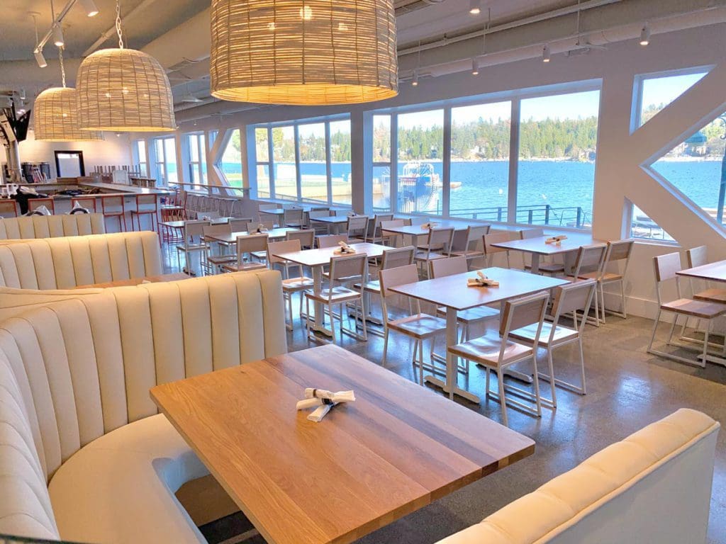The indoor dining area of Jettie’s Waterfront Kitchen + Drink, featuring large windows facing the lake.